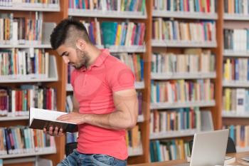 In The Library - Handsome Arabic Male Student With Laptop And Books Working In A High School - University Library - Shallow Depth Of Field