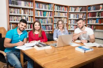 In The Library - Handsome Group Of Students With Laptop And Books Working In A High School - University Library - Shallow Depth Of Field