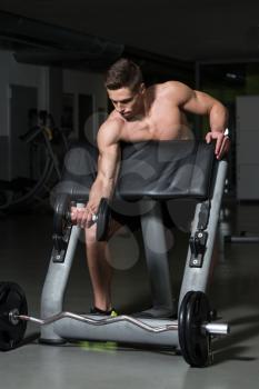 Muscular Young Man Doing Heavy Weight Exercise For Biceps With Dumbbell In Gym