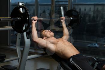 Young Man In Gym Exercising Chest On The Bench Press