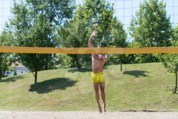 Muscular Young Man Playing Beach Volleyball Diving After The Ball