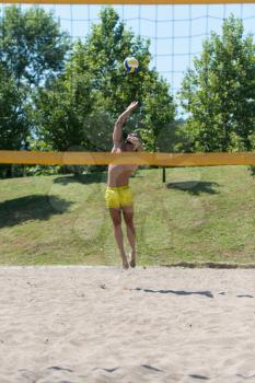 Muscular Young Man Playing Beach Volleyball Diving After The Ball