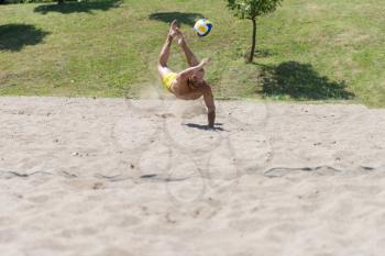 Muscular Young Man Playing Beach Volleyball Diving After The Ball