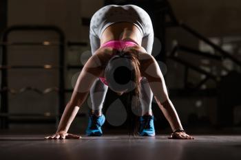 Young Woman Doing Stretching Exercises On The Floor At The Gym