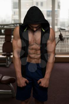 Young Muscular Man In Black Hooded Sweatshirt Showing Muscles
