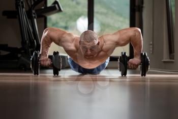 Young Man Push-Up Strength Pushup Exercise With Dumbbell In A Gym Workout