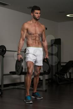 Portrait Of A Young Physically Fit Man Holding Weights And Showing His Well Trained Body