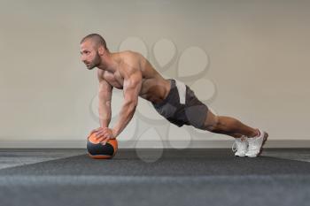 Young Man Exercise With Medical Ball In Fitness Club
