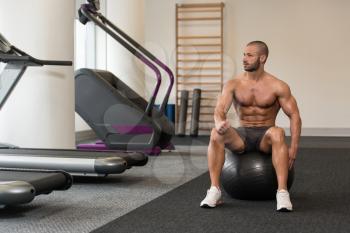 Portrait Of A Muscular Man Resting On Pilates Ball In Fitness Gym