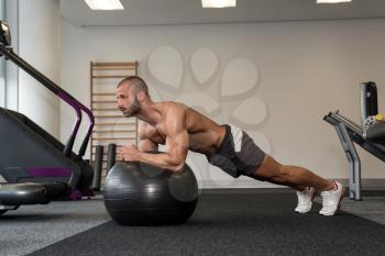 Young Man Exercising Abs On Ball Workout Posture In Fitness Club