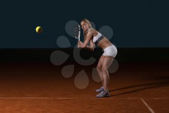 Female Tennis Player Reaching To Hit The Tennis Ball On Court