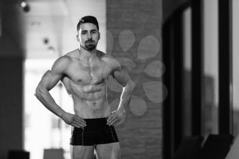 Young Muscular Man Flexing Muscles By Swimming Pool And Sun Loungers