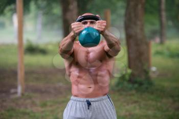 Muscular Adult Caucasian Man Doing A Exercise Outdoors With Kettlebell