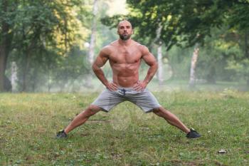 Young Muscular Athlete Doing Stretching As Part Of Bodybuilding Training - Outdoors Workout - Sports And Fitness - Concept Of Healthy Lifestyle - Fitness Male