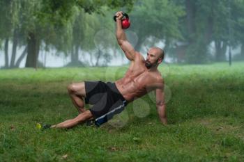 Muscular Fitness Man Balance Kettlebells With One Hand Exercise Outdoors