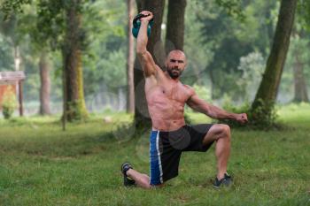 Muscular Fitness Man Balance Kettlebells With One Hand Exercise Outdoors