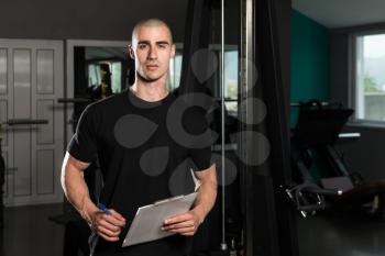 Portrait Of A Personal Trainer In The Gym With Clipboards In His Hands