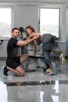 Personal Trainer Showing Young Woman How To Train Back Exercise With Dumbbell In A Gym