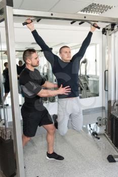 Personal Trainer Showing Young Man How To Train Pull Ups - Chin-Ups In The Gym