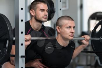 Personal Trainer Showing Young Man How To Train Barbell Squats Exercise In A Health And Fitness Concept