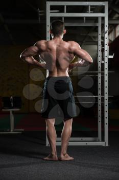 Portrait Of A Young Fit Man Performing Rear Lat Spread Pose - Muscular Athletic Bodybuilder Fitness Model Posing After Exercises