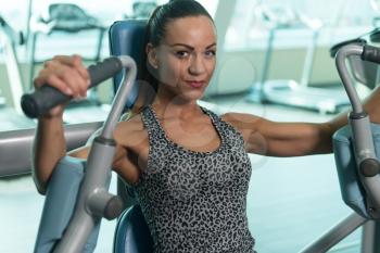 Young Woman Exercising Chest On Machine In The Gym And Flexing Muscles - Muscular Athletic Bodybuilder Fitness Model Exercise In Fitness Center