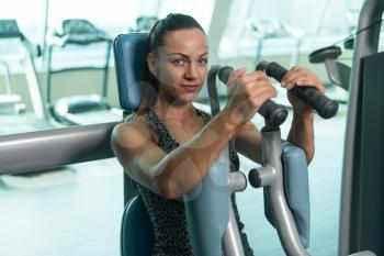 Portrait Of A Young Physically Fit Woman Exercising Chest On Machine - Muscular Athletic Bodybuilder Fitness Model Exercise In A Gym