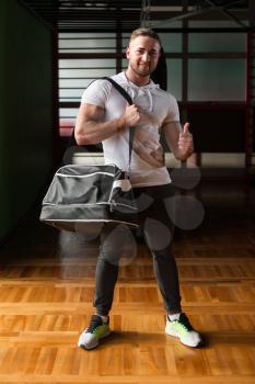 Fit young man with gym bag going on the in gym
