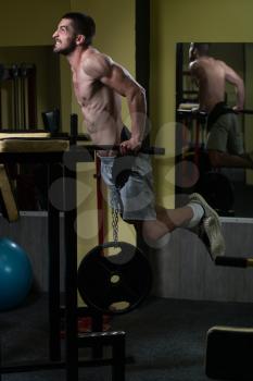 Young Muscular Fitness Bodybuilder Doing Heavy Weight Exercise For Triceps And Chest on Parallel Bars In The Gym