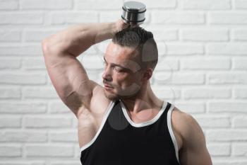Bodybuilder Working Out Triceps With Dumbbells On White Bricks Background With Copyspace