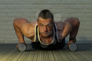 Young Man Doing Pushups With Dumbbells As Part Of Bodybuilding Training