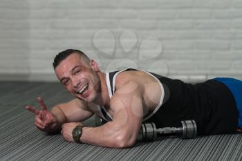 Young Athlete Resting And Showing Peace Sign After Doing Pushups With Dumbbells As Part Of Bodybuilding Training