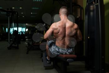 Muscular Athletic Bodybuilder Fitness Model Doing Heavy Weight Exercise For Back On Machine