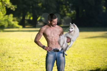 Sexy Young Man Holding Dog German Spitz In Park - Together Enjoying The View
