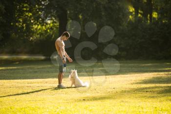 Naked Young Man Holding Dog German Spitz In Park - Together Enjoying The View