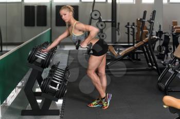Young Woman Exercising Back With Dumbbells In The Gym And Flexing Muscles - Muscular Athletic Bodybuilder Fitness Model