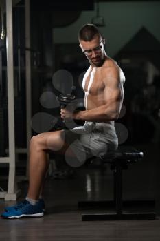 Handsome Man Wearing Glasses Working Out Biceps In A Dark Gym - Dumbbell Concentration Curls