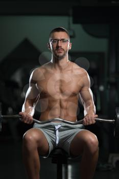 Muscular Nerd Man Doing Heavy Weight Exercise For Biceps With Barbell In Gym