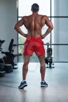 Young Italian Man Standing Strong In The Gym And Flexing Muscles - Muscular Athletic Bodybuilder Fitness Model Posing After Exercises