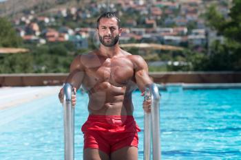 Portrait Of A Wet Sexy Muscular Man Standing In Swimming Pool