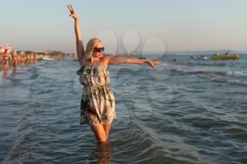 Relaxed Woman In Dress Enjoying Tropical Beach And Caribbean Summer Vacation - Fit Tanned Brunette Enjoying A Walk In The Sea