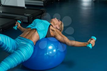 Mature Woman Exercising On Ball In The Gym And Flexing Muscles - Muscular Athletic Bodybuilder Fitness Model
