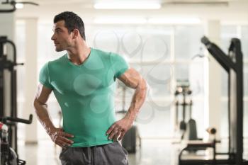 Healthy Young Man in T-shirt Standing Strong and Flexing Muscles - Muscular Athletic Bodybuilder Fitness Model Posing After Exercises