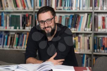 In The Library - Handsome Male Student With Laptop And Books Working In A High School - University Library - Shallow Depth Of Field