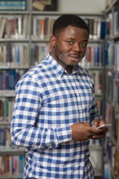 African Male Student Using The Phone In Library - Shallow Depth Of Field