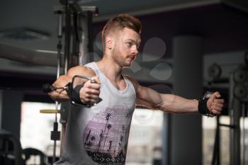 Handsome Muscular Fitness Bodybuilder Doing Heavy Weight Exercise For Chest On Machine With Cable In The Gym