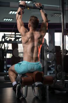Handsome Muscular Fitness Bodybuilder Doing Heavy Weight Exercise For Shoulders On Machine With Cable In The Gym