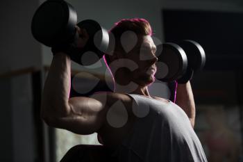 Young Man Working Out Shoulders In A Dark Gym - Dumbbell Concentration Curls
