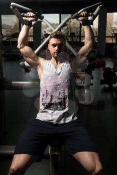 Handsome Muscular Fitness Bodybuilder Doing Heavy Weight Exercise For Shoulders On Machine In The Gym