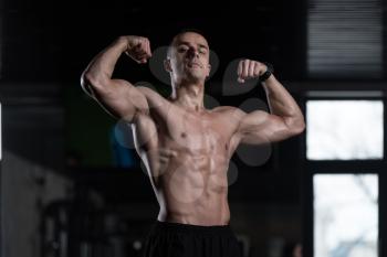 Healthy Man Standing Strong In The Gym And Flexing Muscles - Muscular Athletic Bodybuilder Fitness Model Posing After Exercises